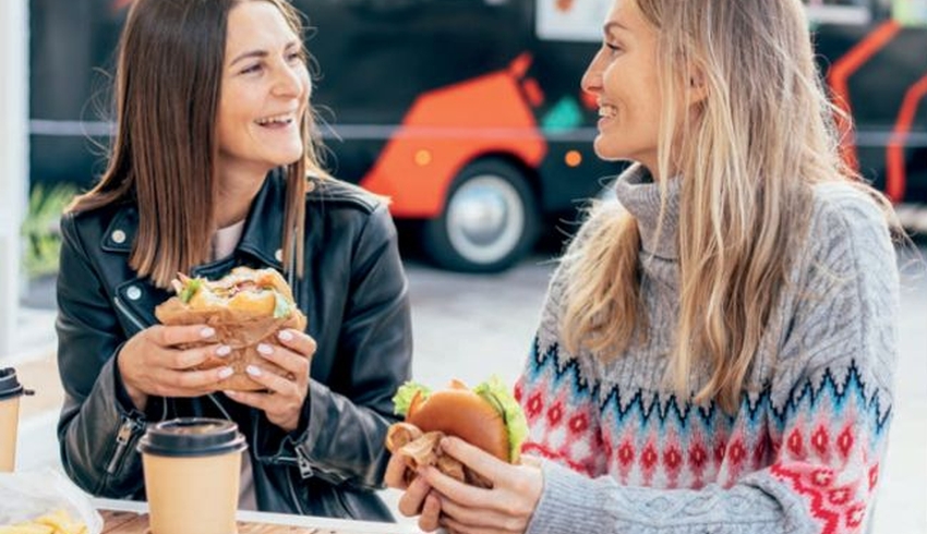 Two women eating burgers outdoors